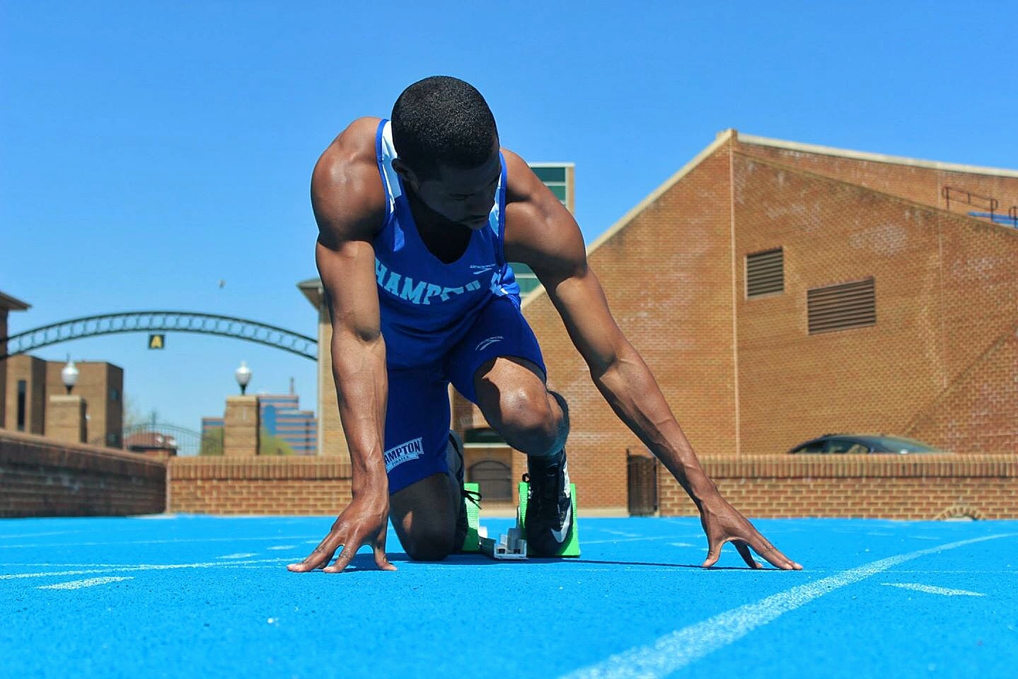A photograph of sprinters crouched in starting blocks on a track, in the set position before a race start.