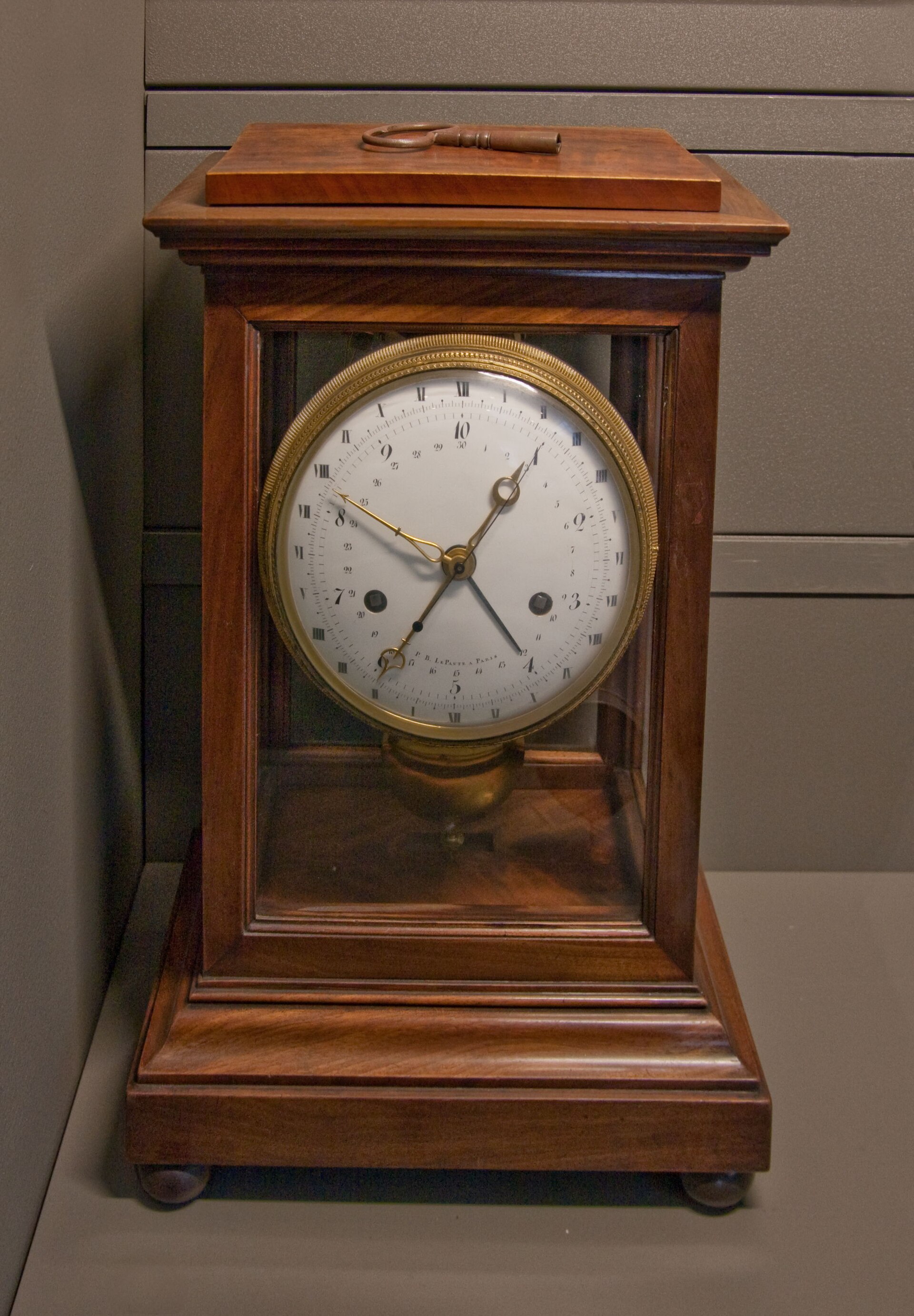 A French Revolutionary mantel clock in a glazed mahogany case, its enamel dial carrying two sets of numerals: Roman numerals I to XII around the outside and Arabic 1 to 10 within.