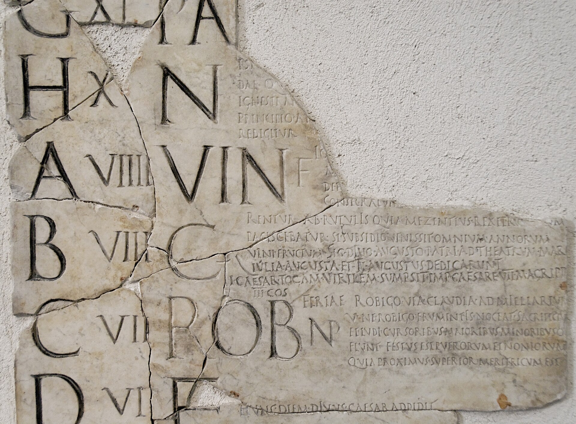 A fragment of the Fasti Praenestini, a painted Roman stone calendar, showing columns of incised letters and abbreviations.
